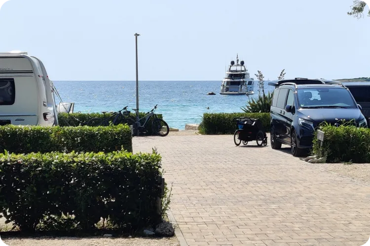Stellplatz mit Blick auf das Meer und eine Yacht auf dem Camping Mon Perin in Kroatien