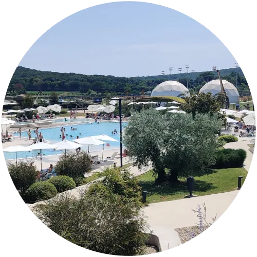 Dinosaurier-förmiger Pool mit Liegen und Sonnenschirmen im Paleo Park des Campingplatzes Mon Perin in San Polo