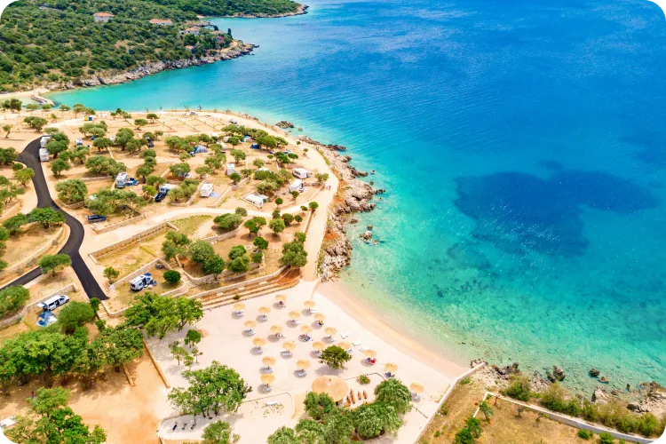 Luftaufnahme des Campingplatzes Olea in Kroatien mit türkisblauem Wasser, Sandstrand, Zelten und Wohnmobilen direkt am Meer, umgeben von mediterraner Vegetation