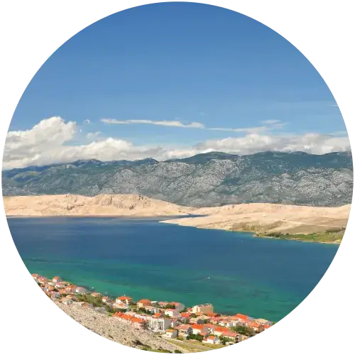 Panoramaansicht der kargen Landschaft der Insel Pag mit Küstendorf, Velebit-Gebirge und türkisblauem Meer
