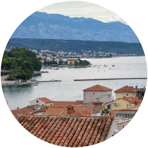 Panoramablick über die Altstadt von Pag mit roten Dächern, Bucht und Velebit-Gebirge auf der Insel Pag in Kroatien