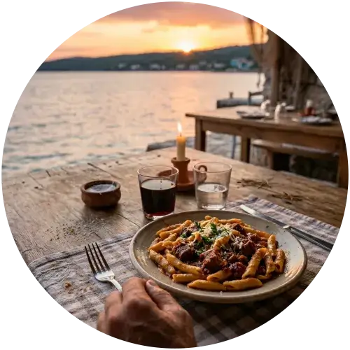 Surlice Nudeln mit kräftigem Gulasch – Abendessen in einer Taverne am Meer, Kroatien Teller mit Surlice Nudeln und kräftigem Gulasch auf einem Holztisch in einer rustikalen Taverne direkt am Meer – Kerzenlicht, Rotwein und Sonnenuntergang im Hintergrund, Kroatien