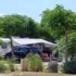 Ein Stellplatz auf dem Campingplatz Omišalj mit einem geparkten Wohnwagen, einem davorstehenden schwarzen Pkw und einem ausgefahrenen Vorzelt, umgeben von schattenspendenden Bäumen.